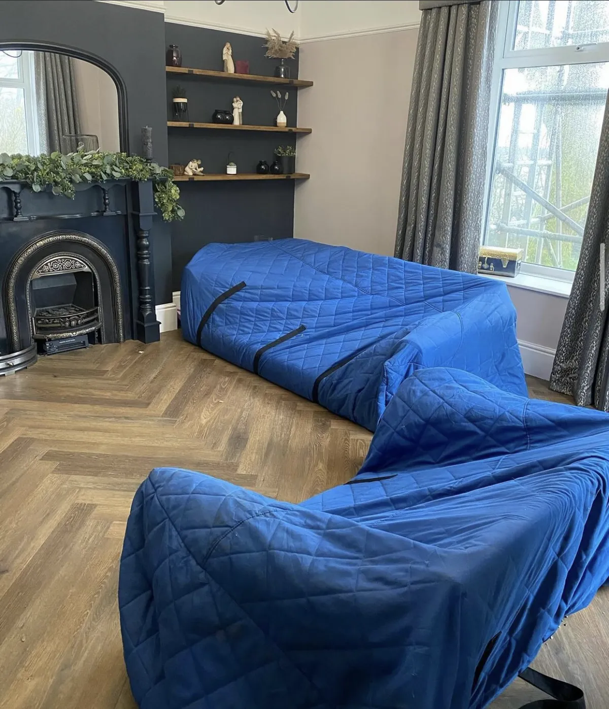 Furniture wrapped in blue quilted covers on a herringbone floor, ready for Bridge Removals storage. Furniture wrapped in blue quilted covers on a herringbone floor, ready for Bridge Removals storage.